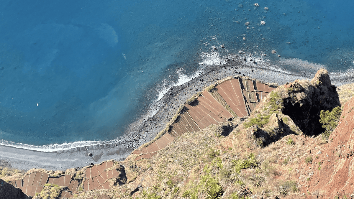 View from a steep cliff overlooking an ocean shoreline